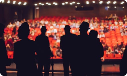 silhouettes of 5 perfomers on stage with the audience behind them